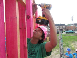 Person with pink hardhat drilling.