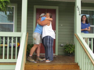 People embracing on porch of new home.